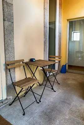 a picnic table and two chairs next to a wall at Casa da Oliveira in Porto