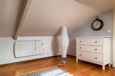 a white vase sitting on a dresser in a room with a clock at Casa da Oliveira in Porto