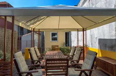 a patio with a table and chairs under a large umbrella at Casa da Oliveira in Porto