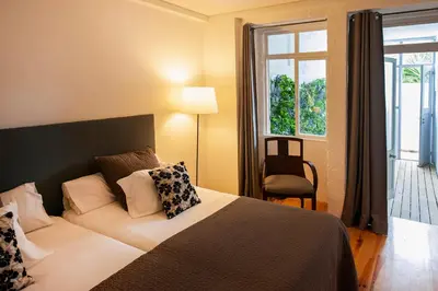 a bedroom with a bed and a window and a chair at OportoHouse in Porto