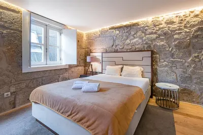 a bedroom with a large bed in a stone wall at GuestReady - The New Yellow Ledbetter in Porto