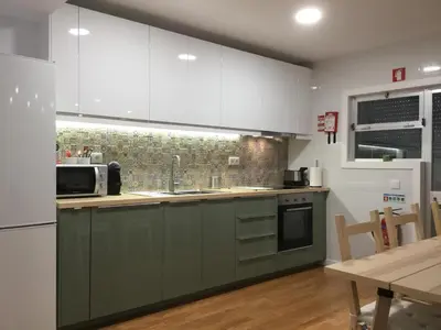 a kitchen with green and white cabinets and a table at My Portugal for All - Oporto Flat in Vila Nova de Gaia