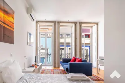 a living room with a blue couch in a room with windows at Bright Apartment • Downtown Porto in Porto