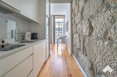 a kitchen with a stone wall and a wooden floor at Bright Apartment • Downtown Porto in Porto