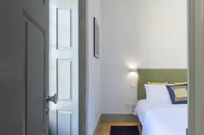 a bedroom with a white bed and a door at Casa Amarela in Porto