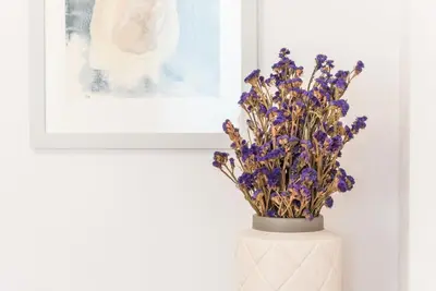 a vase with purple flowers in it next to a painting at GuestReady - Warm cocoa retreat in Cedofeita in Porto