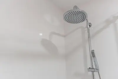 a shower head in a bathroom with a white wall at GuestReady - Warm cocoa retreat in Cedofeita in Porto
