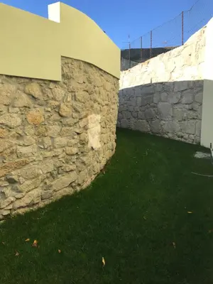 a stone wall with green grass next to it at Secret Camões in Porto