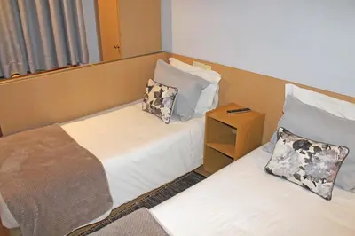 a room with two beds and a night stand at Residencial Paranhos in Porto