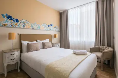 a bedroom with a large bed and a chair at Camarinha Oporto Apartments in Porto