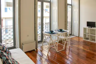 a living room with a table and chairs and windows at Bonjardim Flats - T1 com varanda in Porto