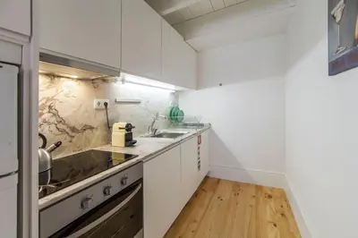 a kitchen with white cabinets and a wooden floor at Oporto Mezzanine - by ML Apartments in Porto