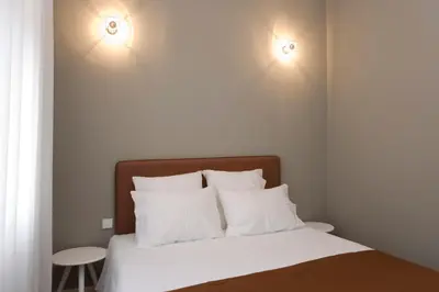 a bedroom with a bed with two lights on the wall at De Porto e Alma in Porto