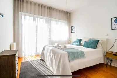 a white bedroom with a large bed and a window at LAZ apartment in Porto