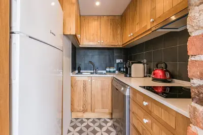 a kitchen with wooden cabinets and a white refrigerator at GuestReady - Crayon Walls Apartments in Porto