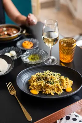 a table with a plate of food and a glass of wine at Pestana Porto - A Brasileira, City Center & Heritage Building in Porto