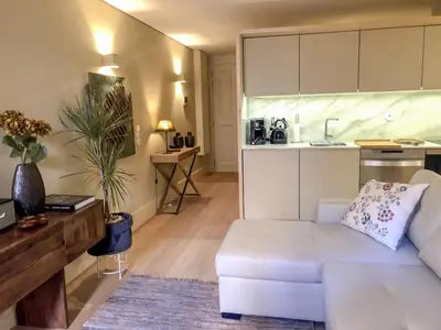 a living room with a white couch and a kitchen at HOMEinTOWN Almada - Downtown Elegant Apartment - Terrace AC & WIFI in Porto