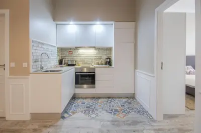 a kitchen with white cabinets and a tile floor at OHH -S João apartments- Riverside in Porto