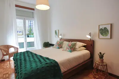 a bedroom with a bed with a green blanket on it at Virtudes Patio in Porto