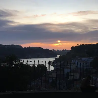 a sunset behind a fence with a view of a river at Virtudes Patio in Porto