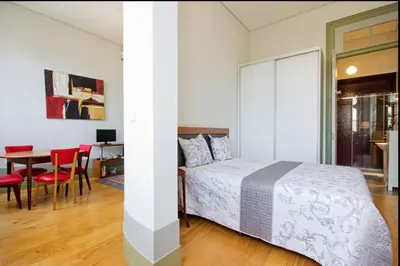a bedroom with a bed and a table with red chairs at HeartMade Loft & Heartmade Studio in Porto