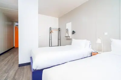 two beds in a room with white walls and wood floors at STAYSOME Porto Herculano in Porto