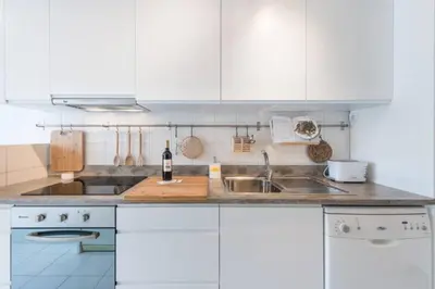 a white kitchen with a sink and a bottle of wine at GuestReady - Cn Apartment in Porto