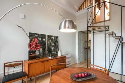 a dining room with a table and a spiral staircase at Visconde Mezzanine in Porto