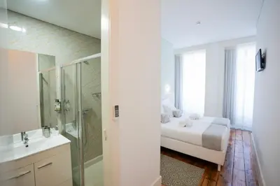 a bedroom with a bed and a shower and a sink at Turista Da Trindade in Porto