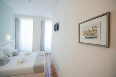 a white room with a bed and a picture on the wall at Turista Da Trindade in Porto