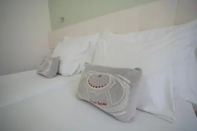 a white bed with white pillows and a pillow on it at Turista Da Trindade in Porto