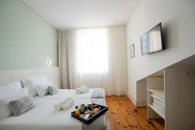 a bedroom with a white bed with a tray of food on it at Turista Da Trindade in Porto