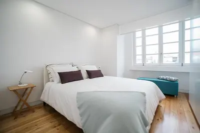 a white bedroom with a large white bed and windows at D'Autor Apartments Sá da Bandeira in Porto