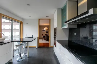 a kitchen with a black counter top and a dining room at Comfy Luxury Apartment in Porto
