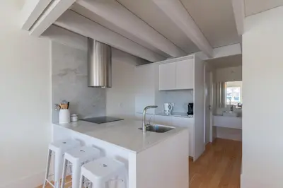 a white kitchen with white cabinets and white stools at FLH Douro View Luxury Duplex in Porto