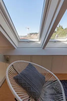 a white rattan chair in front of a window at FLH Douro View Luxury Duplex in Porto