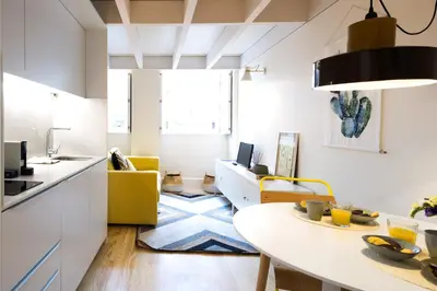 a kitchen and living room with a table and yellow chairs at Studio Tomás Gonzaga in Porto