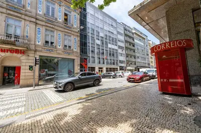 a red phone booth on a city street with cars at Merc Porto Bolhão Place in Porto