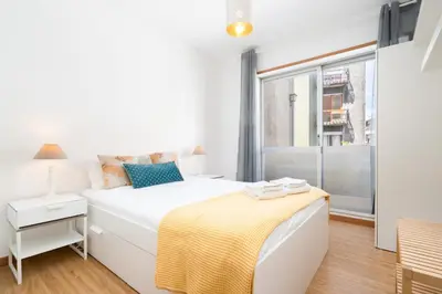 a white bedroom with a bed and a window at Renovated 3BR Apt Near City Hotspots with Great Value in Porto