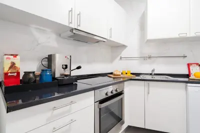 a kitchen with white cabinets and black counter tops at Renovated 3BR Apt Near City Hotspots with Great Value in Porto