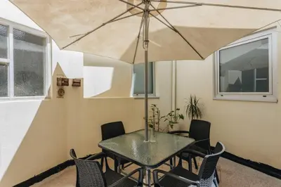 a table with chairs and an umbrella in a room at Cozy 1-Bedroom with Private Terrace in Palmela in Porto