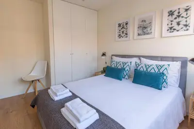 a bedroom with a large white bed with blue pillows at Oporto Between Walls by the center with A/C in Porto