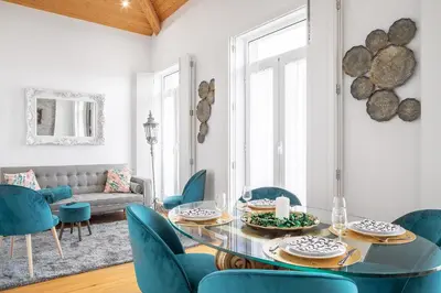 a living room with a glass table and blue chairs at Downtown Historic Apartments in Porto