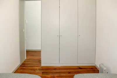 a bedroom with white cabinets and a wooden floor at Bonjardim Flats - T1 in Porto