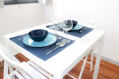 a white table with two plates and wine glasses at Bonjardim Flats - T1 in Porto