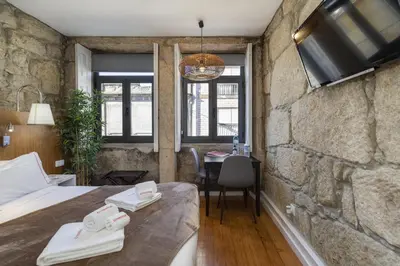a bedroom with a bed with a tv on a stone wall at Oporto Gardens - Historic House, by Hopstays in Porto