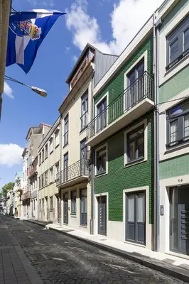 a green and white building on a city street at Charming City Centre Studio near Aliados - Inside Porto Apartments 