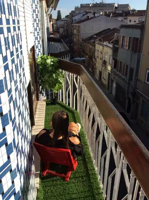 a woman sitting in a red chair on a balcony at Downtown Sunny Apartment in Porto