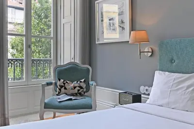 a bedroom with a bed and a chair and a window at Villa Mouzinho by ON Apartments in Porto