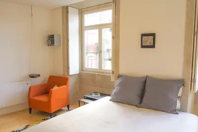 a bedroom with a bed and an orange chair at Taipas Plaza @ Historical Center in Porto
